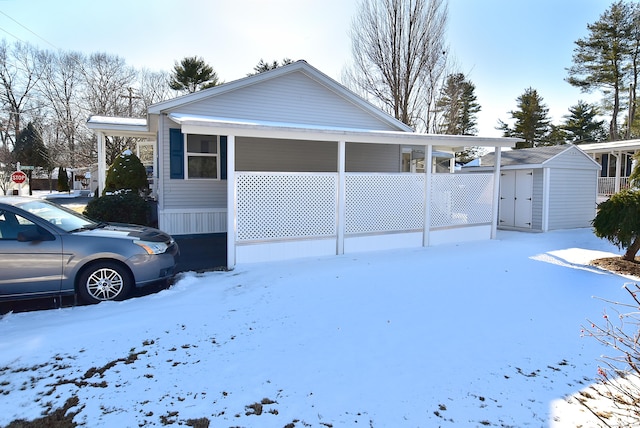 view of snow covered exterior featuring a carport and a storage unit