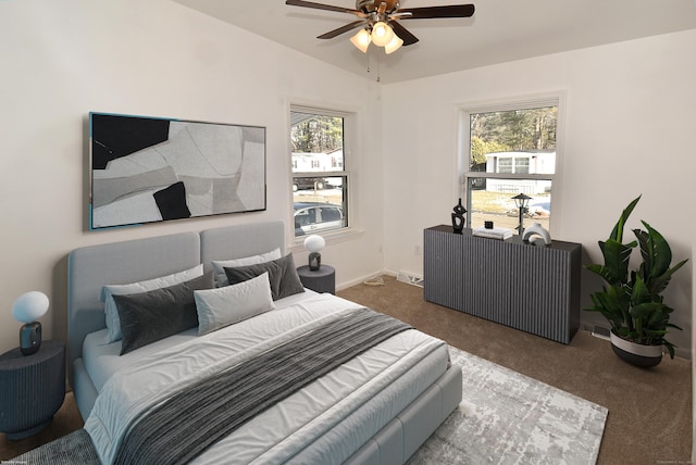 bedroom with multiple windows, dark carpet, vaulted ceiling, and ceiling fan