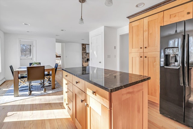 kitchen featuring pendant lighting, black fridge with ice dispenser, a center island, and light brown cabinets