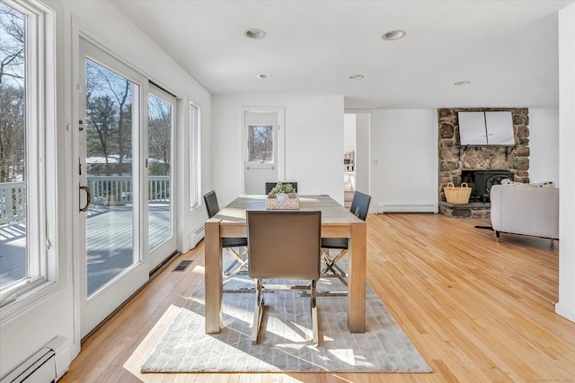 dining room featuring baseboard heating, light hardwood / wood-style floors, and a wealth of natural light