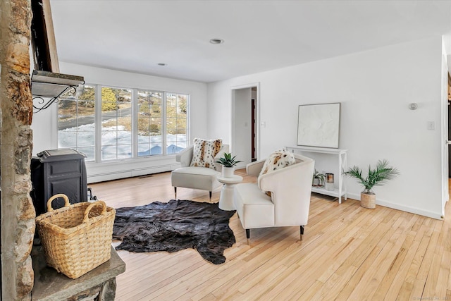 living area featuring a baseboard heating unit and light hardwood / wood-style floors