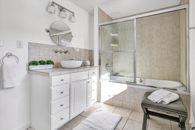 bathroom featuring vanity, combined bath / shower with glass door, tile patterned floors, and decorative backsplash