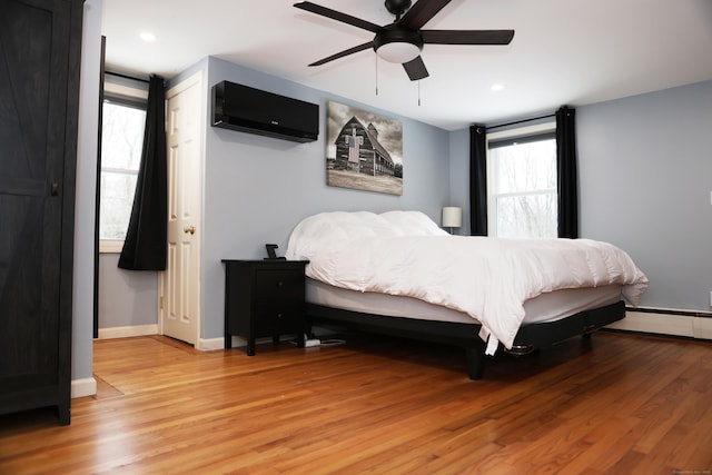 bedroom with a baseboard radiator, hardwood / wood-style flooring, and ceiling fan