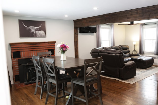 dining area with radiator heating unit, dark hardwood / wood-style flooring, and a fireplace