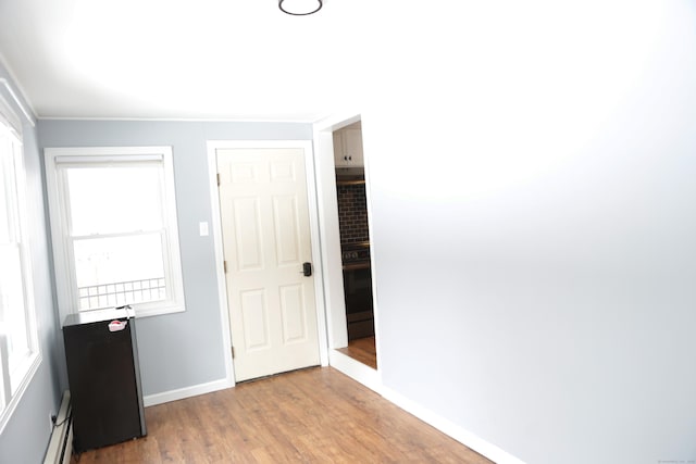 unfurnished bedroom featuring wood-type flooring and a baseboard heating unit