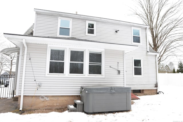 snow covered back of property featuring a hot tub