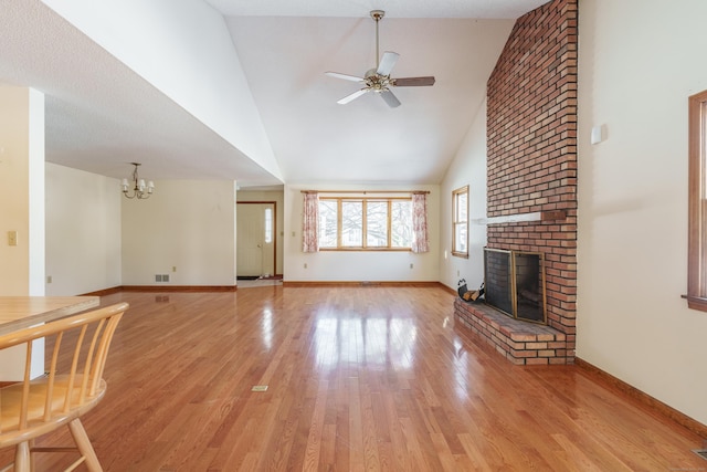 unfurnished living room featuring high vaulted ceiling, a fireplace, ceiling fan with notable chandelier, and light wood-type flooring