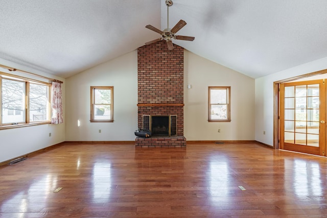 unfurnished living room with a brick fireplace, a wealth of natural light, and light hardwood / wood-style floors