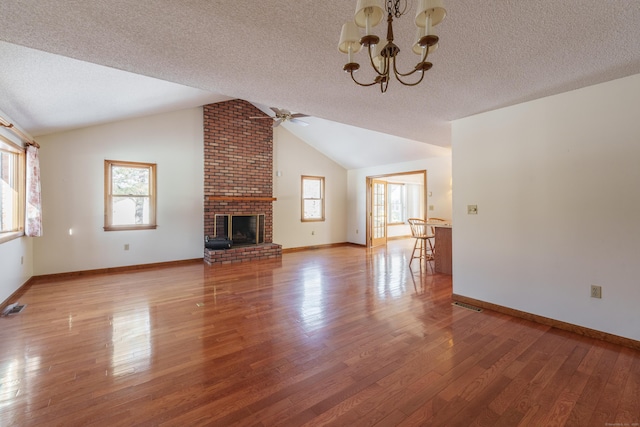 unfurnished living room featuring a brick fireplace, vaulted ceiling, hardwood / wood-style floors, and a textured ceiling