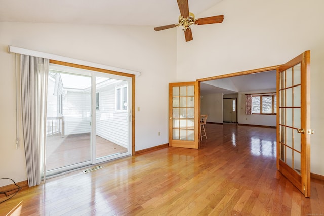 unfurnished room with ceiling fan, high vaulted ceiling, light hardwood / wood-style floors, and french doors