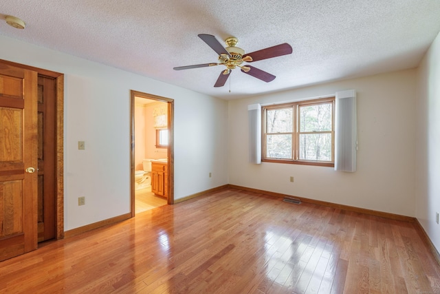 unfurnished bedroom with connected bathroom, a textured ceiling, light hardwood / wood-style flooring, and ceiling fan