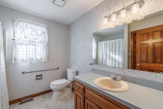 bathroom with vanity, toilet, and a textured ceiling