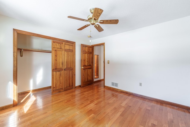 unfurnished bedroom with light wood-type flooring, ceiling fan, and a closet