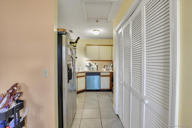 kitchen featuring light tile patterned floors, stainless steel appliances, and cream cabinetry