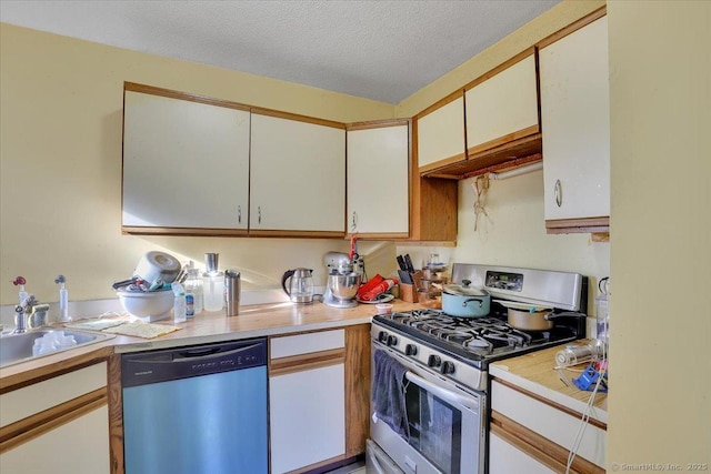 kitchen featuring sink, a textured ceiling, stainless steel appliances, and white cabinets