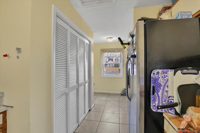 kitchen featuring light tile patterned floors, stainless steel fridge, and a textured ceiling