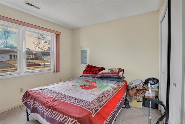 bedroom featuring light tile patterned flooring, electric panel, and a textured ceiling