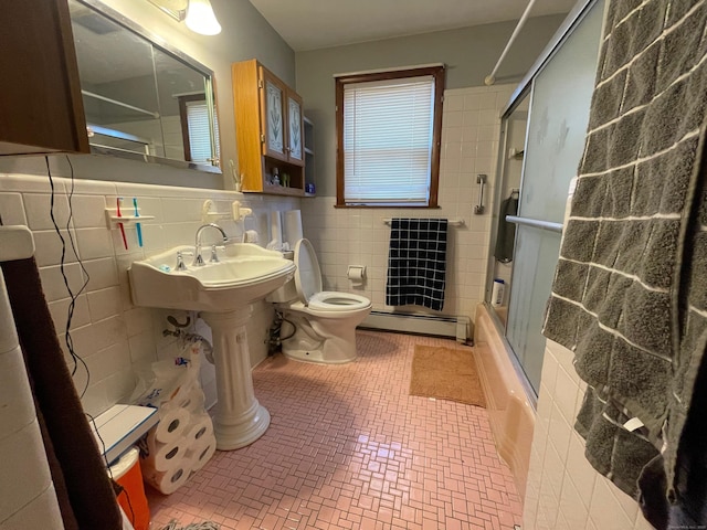 bathroom featuring a baseboard radiator, toilet, combined bath / shower with glass door, and tile walls