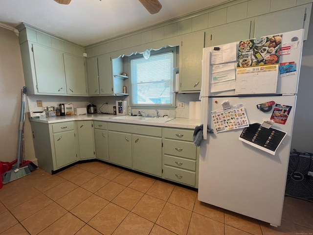 kitchen with sink, light tile patterned floors, ceiling fan, and white fridge