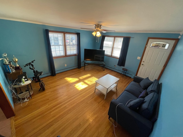 living room with a baseboard heating unit, crown molding, ceiling fan, and light wood-type flooring