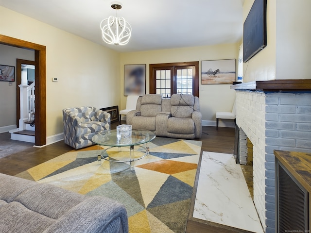 living room featuring an inviting chandelier, a fireplace, and dark wood-type flooring