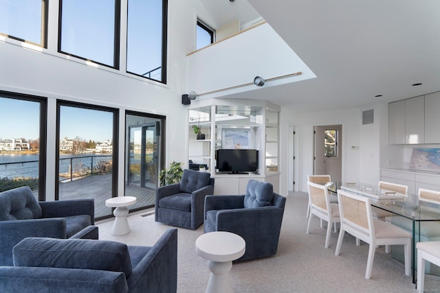 living room with light carpet, a high ceiling, and a water view