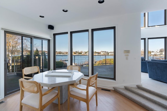 dining room featuring a water view and light hardwood / wood-style flooring