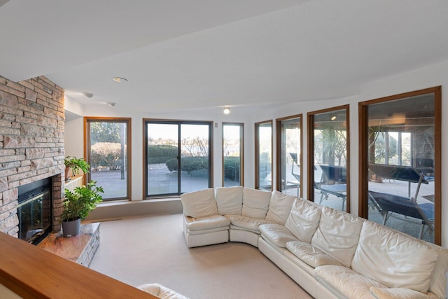 unfurnished living room featuring a stone fireplace and carpet floors