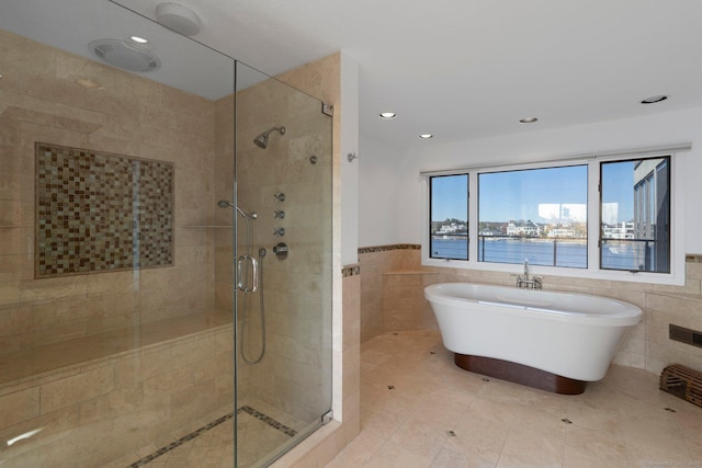 bathroom featuring plus walk in shower, a water view, and tile walls