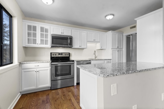 kitchen featuring sink, light stone counters, appliances with stainless steel finishes, dark hardwood / wood-style floors, and white cabinets