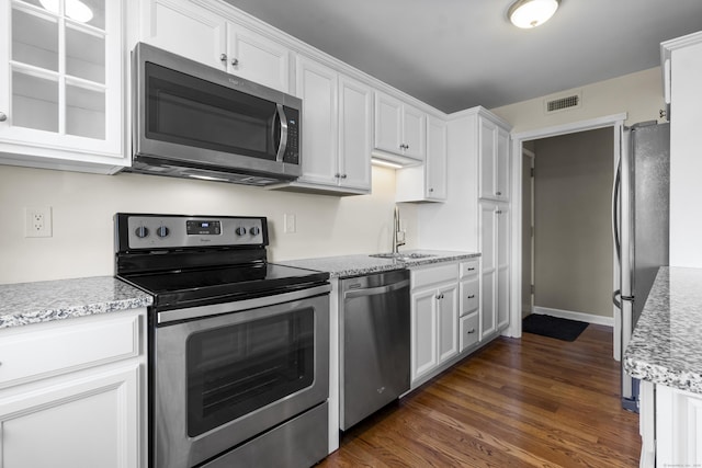 kitchen featuring dark wood-type flooring, sink, stainless steel appliances, light stone countertops, and white cabinets