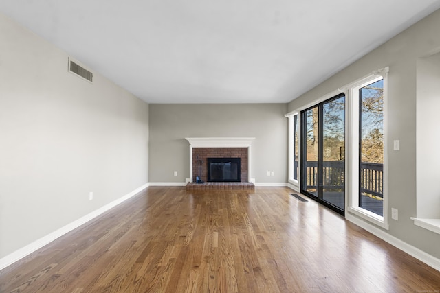 unfurnished living room with hardwood / wood-style floors and a brick fireplace