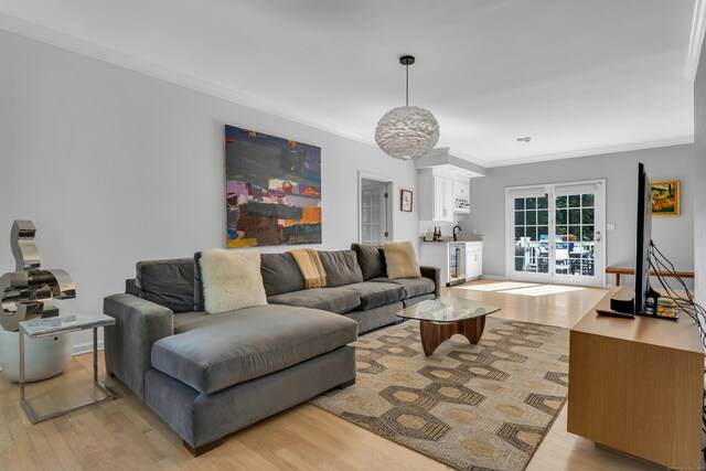 living room featuring crown molding, beverage cooler, and light hardwood / wood-style flooring