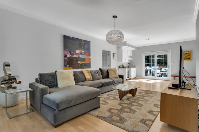 living room with light wood-style floors, beverage cooler, and ornamental molding