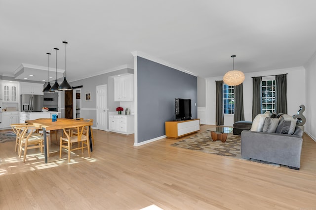 living area featuring ornamental molding, light wood-type flooring, and baseboards