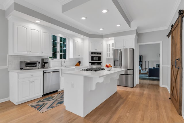 kitchen featuring a barn door, a kitchen island, appliances with stainless steel finishes, and white cabinets