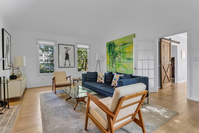 living room featuring a barn door, lofted ceiling, and light hardwood / wood-style flooring