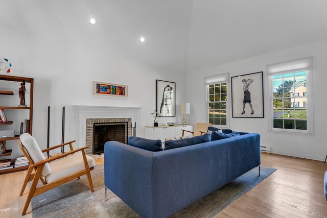 living room featuring hardwood / wood-style floors, a fireplace, high vaulted ceiling, and a baseboard heating unit