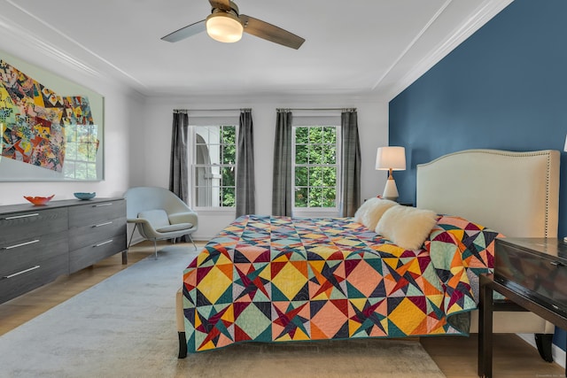 bedroom featuring ceiling fan, ornamental molding, and light wood-type flooring