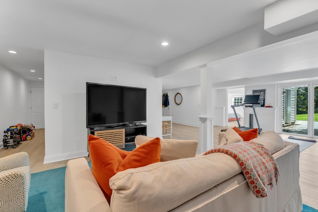 living room featuring baseboards, light wood finished floors, decorative columns, and recessed lighting