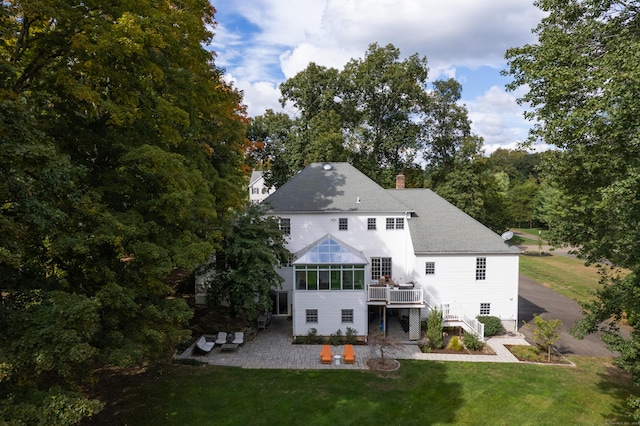 rear view of property featuring a deck, a patio, and a lawn