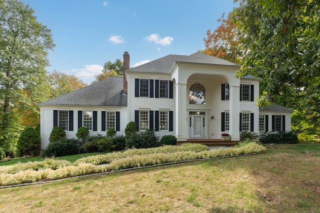 greek revival inspired property with a chimney and a front lawn