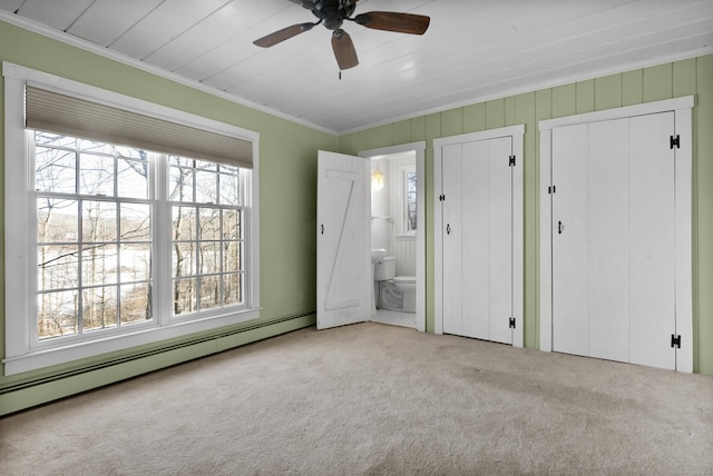 unfurnished bedroom featuring crown molding, ensuite bath, light carpet, multiple closets, and a baseboard radiator