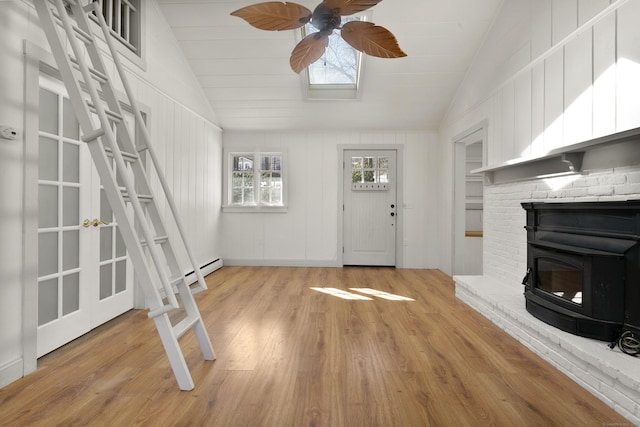 unfurnished living room with light hardwood / wood-style flooring, vaulted ceiling, and a wood stove