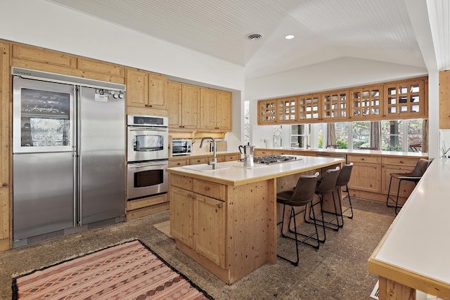 kitchen featuring appliances with stainless steel finishes, a breakfast bar, lofted ceiling, sink, and a kitchen island with sink