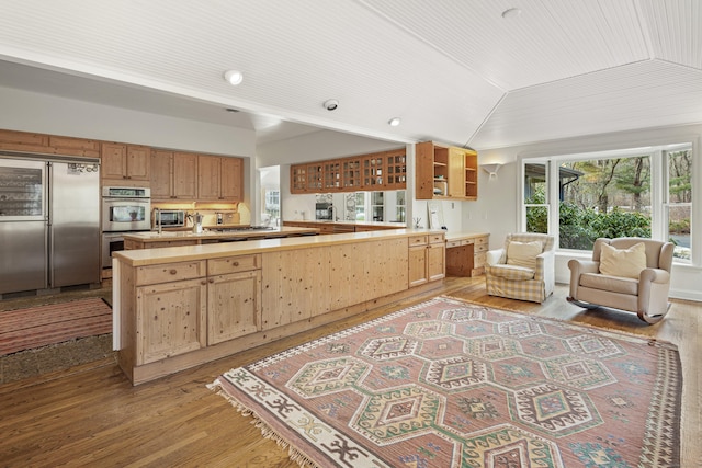 kitchen featuring vaulted ceiling, appliances with stainless steel finishes, butcher block countertops, and light hardwood / wood-style floors