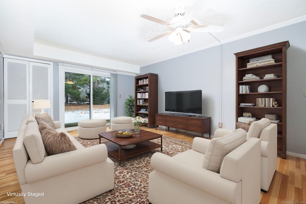 living room featuring ceiling fan, ornamental molding, light hardwood / wood-style floors, and a textured ceiling