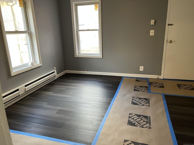 unfurnished room with a baseboard radiator, wood finished floors, a wealth of natural light, and baseboards