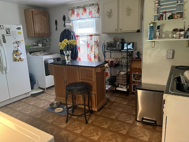 kitchen with washer / dryer, a center island, brown cabinets, and freestanding refrigerator