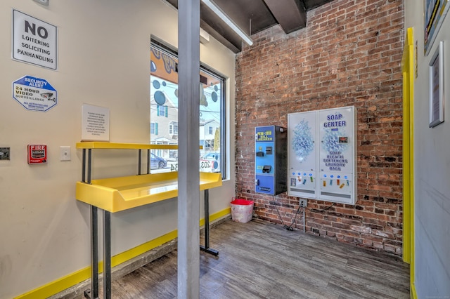 interior space featuring hardwood / wood-style flooring and brick wall